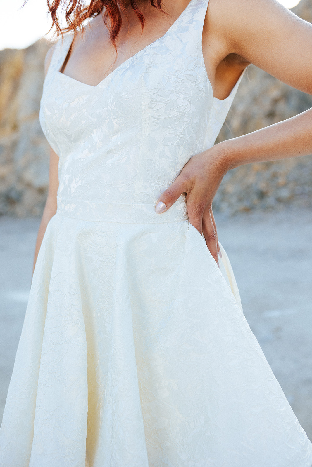 Femme rousse portant une robe de mariée de créateur asymétrique sur-mesure.