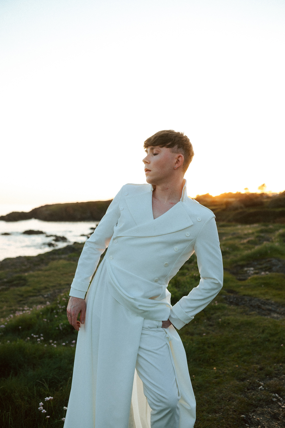 Homme portant un costume de mariage avec un dos nu en dentelle sur-mesure en bord de mer.