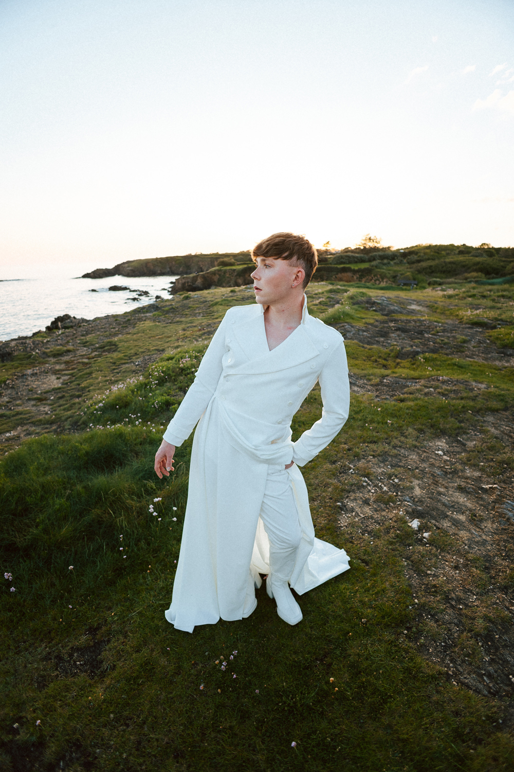 Homme portant un costume de mariage avec un dos nu en dentelle sur-mesure en bord de mer.