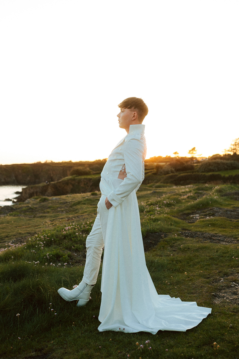 Homme portant un costume de mariage avec un dos nu en dentelle sur-mesure en bord de mer.