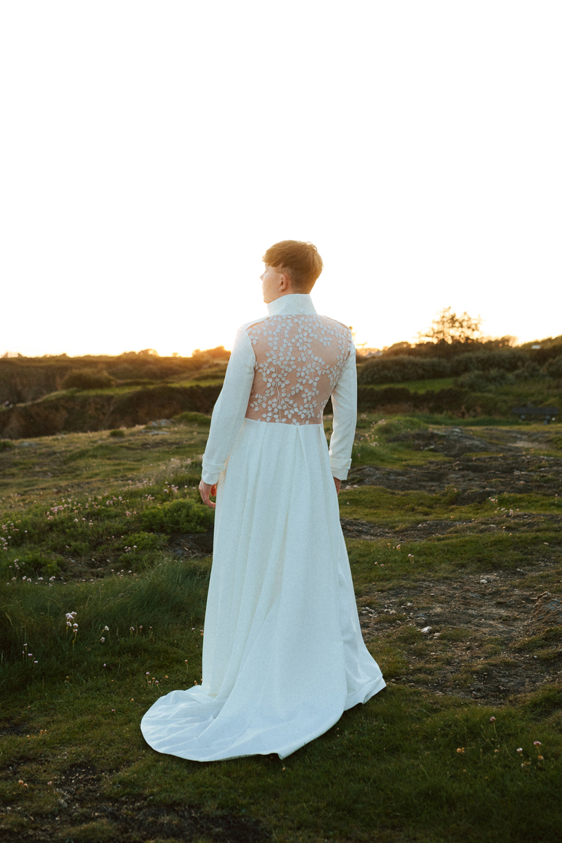 Homme portant un costume de mariage avec un dos nu en dentelle sur-mesure en bord de mer.