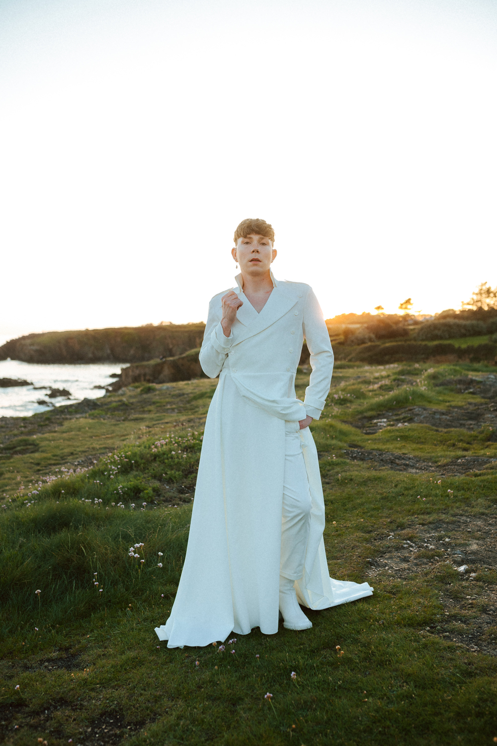 Homme portant un costume de mariage avec un dos nu en dentelle sur-mesure en bord de mer.