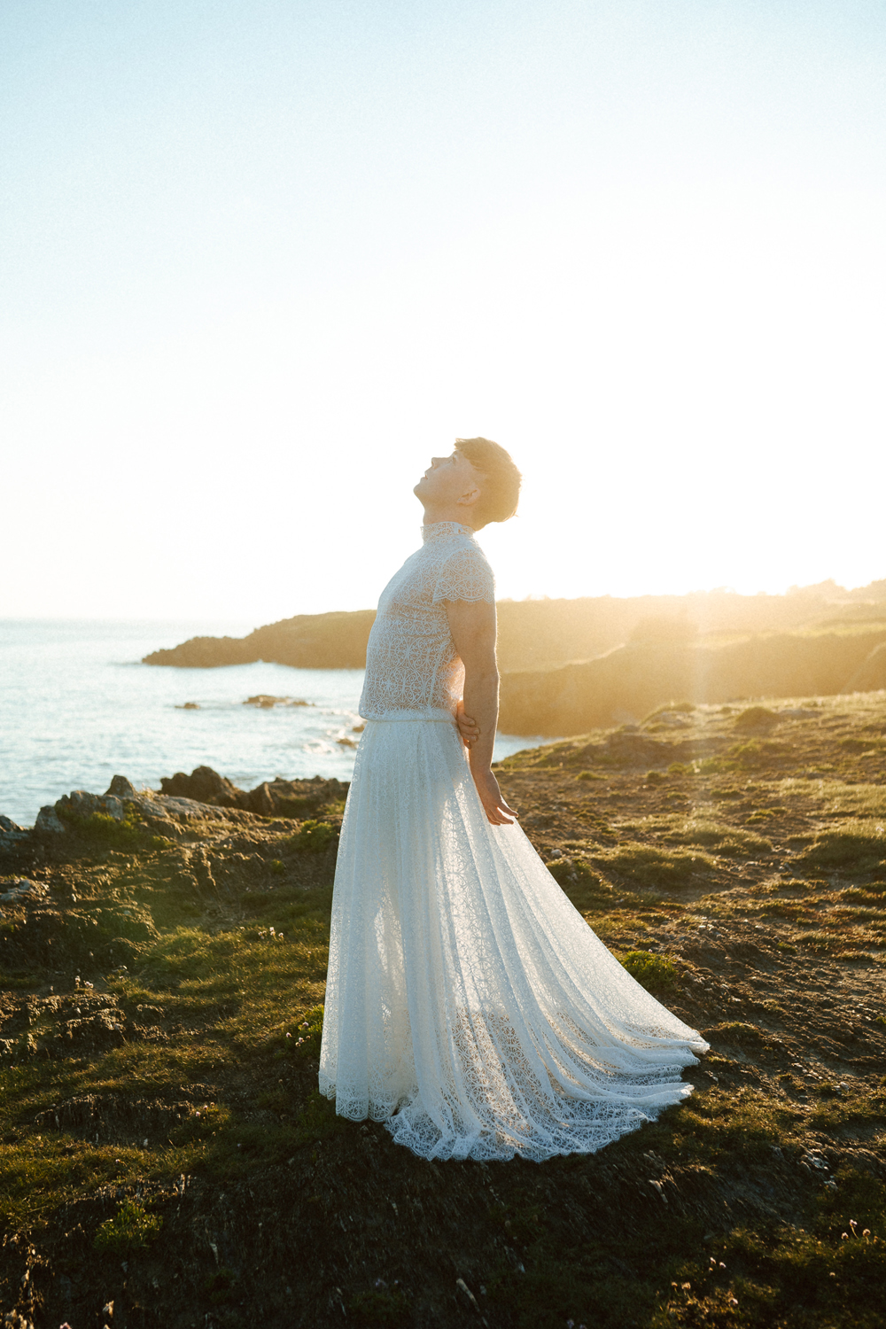 Homme portant un robe de mariage en dentelle sur-mesure en bord de mer.