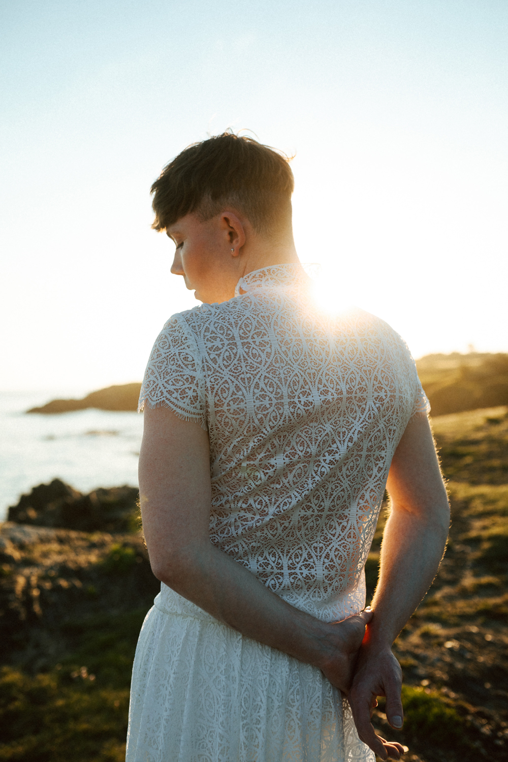 Homme portant un robe de mariage en dentelle sur-mesure en bord de mer.