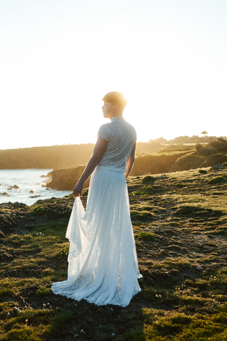 Homme portant un robe de mariage en dentelle sur-mesure en bord de mer.
