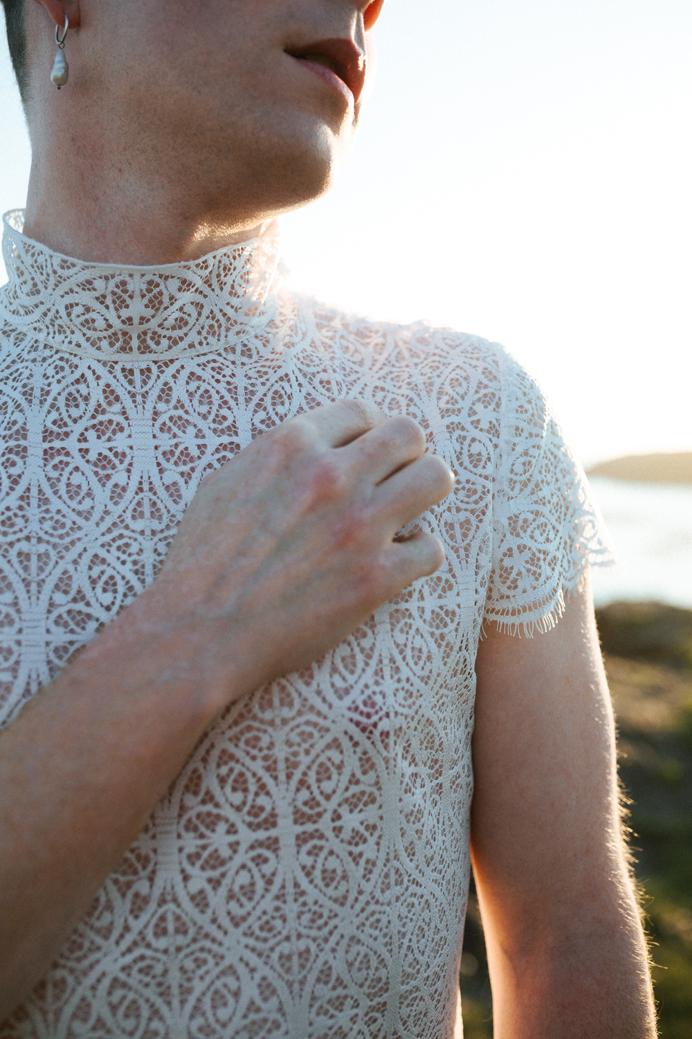 Homme portant un robe de mariage en dentelle sur-mesure en bord de mer.