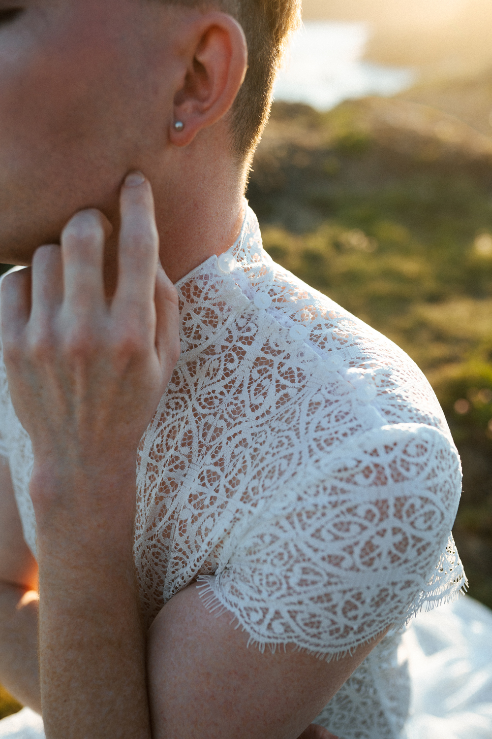 Homme portant un robe de mariage en dentelle sur-mesure en bord de mer.