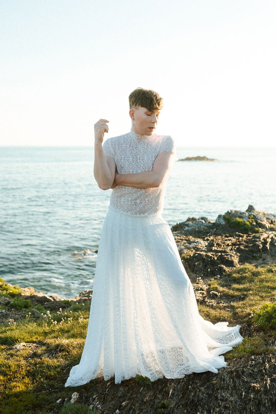 Homme portant un robe de mariage en dentelle sur-mesure en bord de mer.