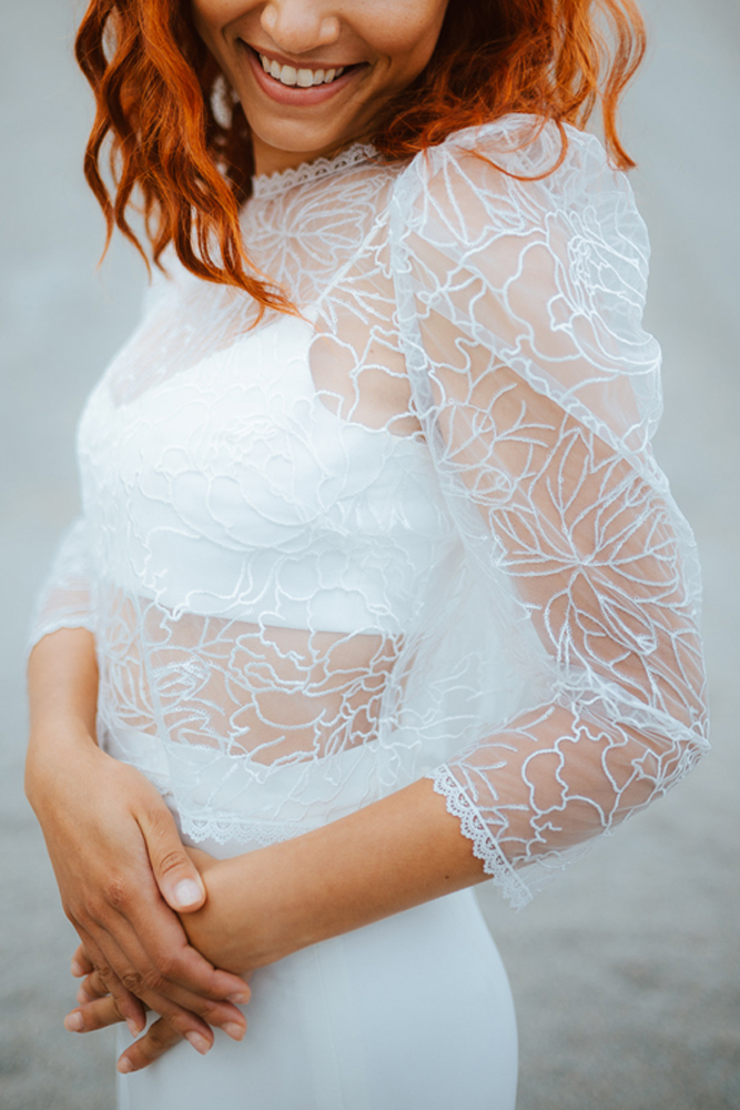 Femme rousse portant une robe de mariée de créateur sirène en dentelle sur-mesure en Bretagne.