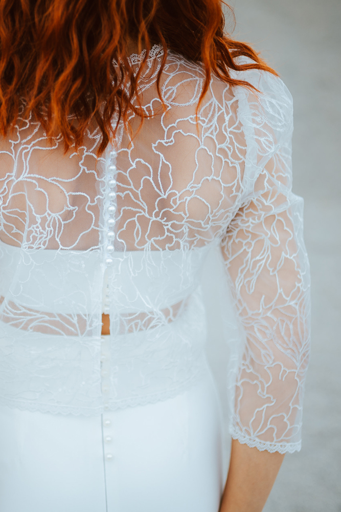 Femme rousse portant une robe de mariée de créateur sirène en dentelle sur-mesure en Bretagne.