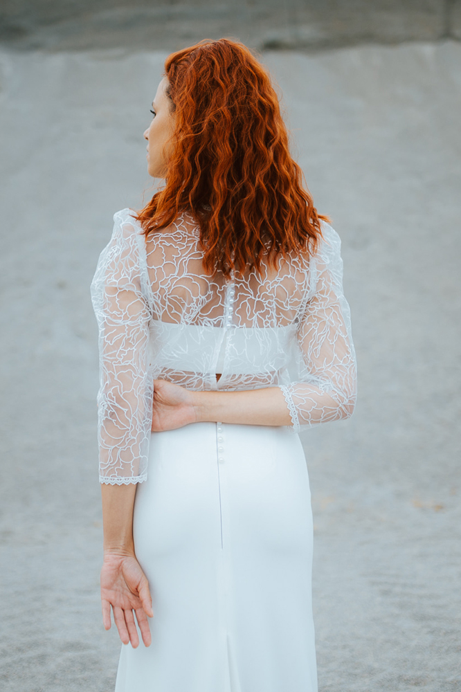 Femme rousse portant une robe de mariée de créateur sirène en dentelle sur-mesure en Bretagne.