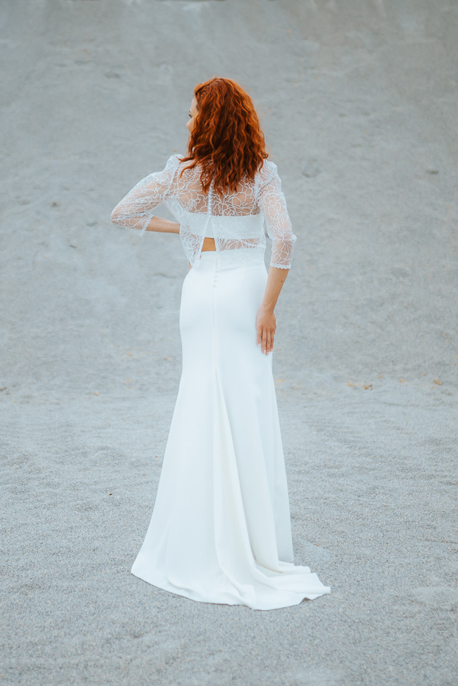 Femme rousse portant une robe de mariée de créateur sirène en dentelle sur-mesure en Bretagne.