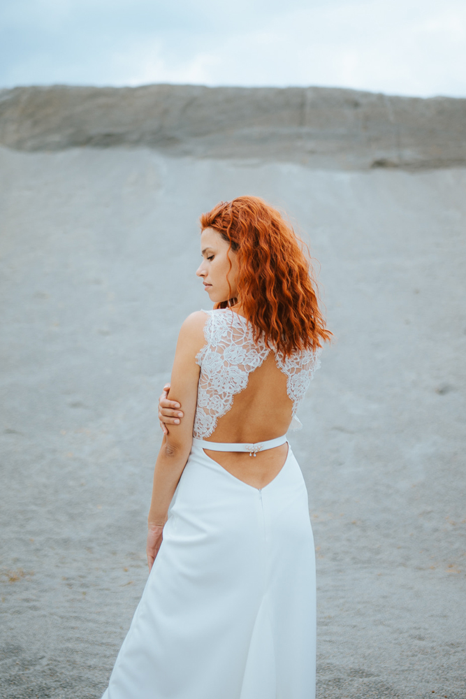 Femme rousse portant une robe de mariée bohème de créateur en dentelle sur-mesure en Bretagne.