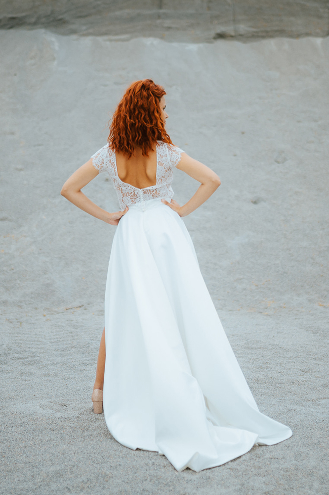 Femme rousse portant une robe de mariée princesse de créateur en dentelle sur-mesure en Bretagne.