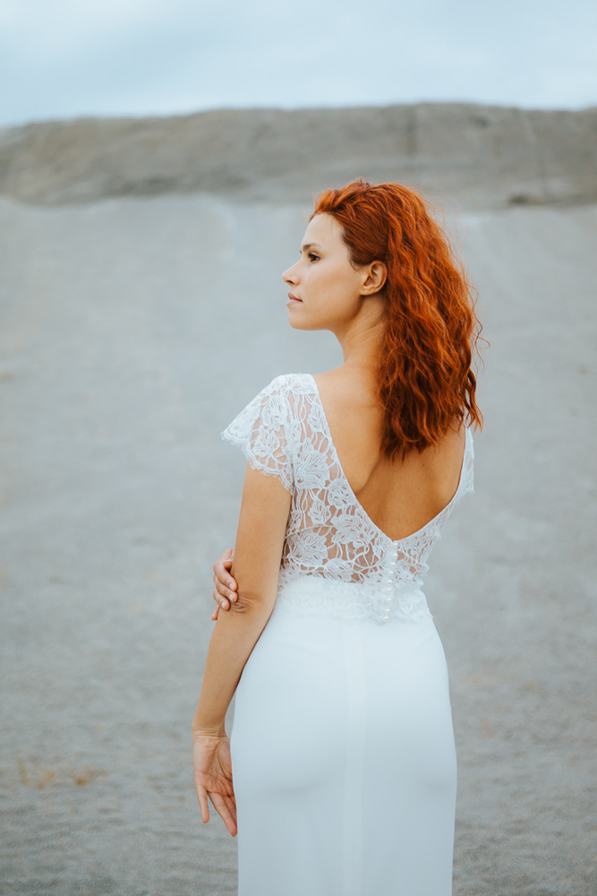 Femme rousse portant une robe de mariée sirène de créateur en dentelle sur-mesure en Bretagne.